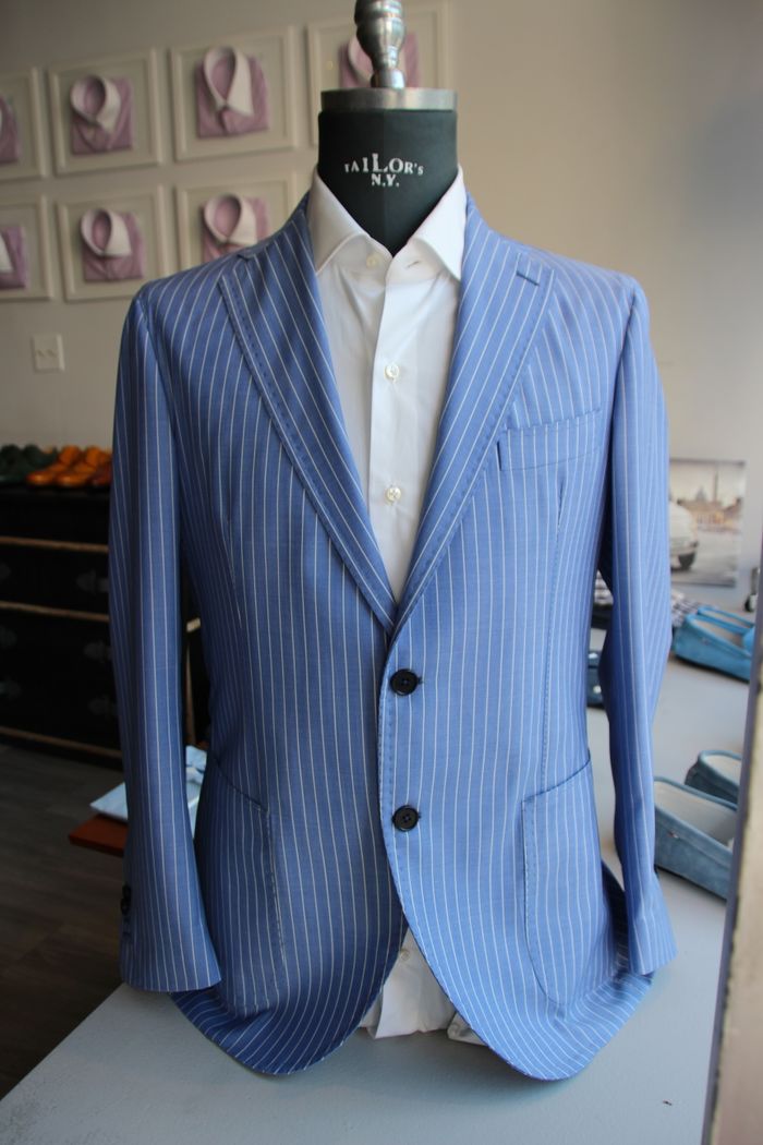 creative-03 Stylish blue pinstripe suit showcased on a mannequin in a tailor's studio.
