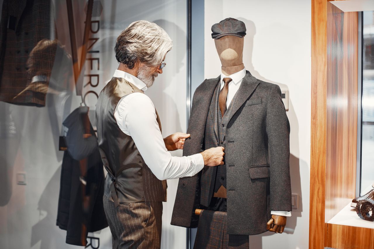 Crafting Captivating Headlines: Your awesome post title goes here Man adjusting a tailored suit on a mannequin in a formal wear store, highlighting fashion elegance and craftsmanship.