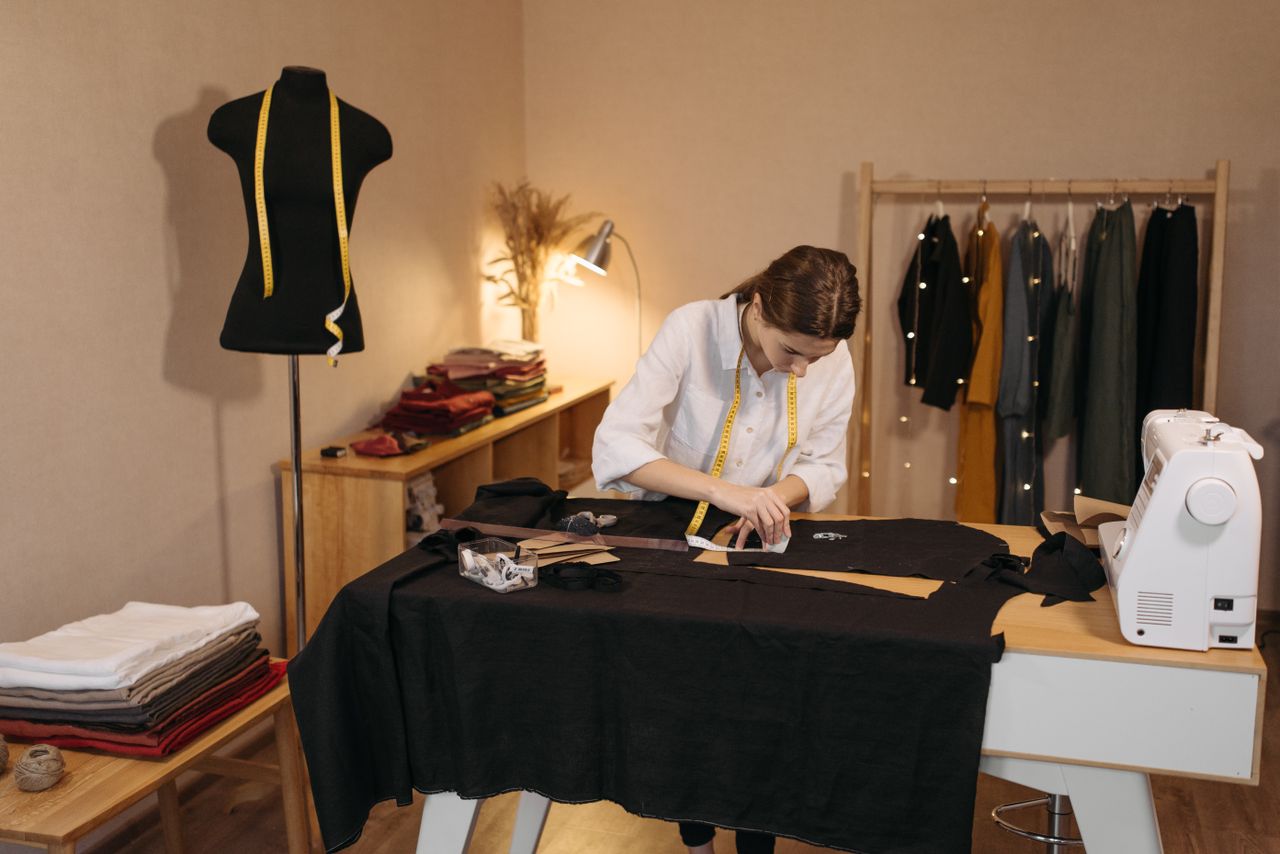 The Art of Drawing Readers In: Your attractive post title goes here A woman involved in dressmaking tasks in a studio, measuring and cutting fabric.