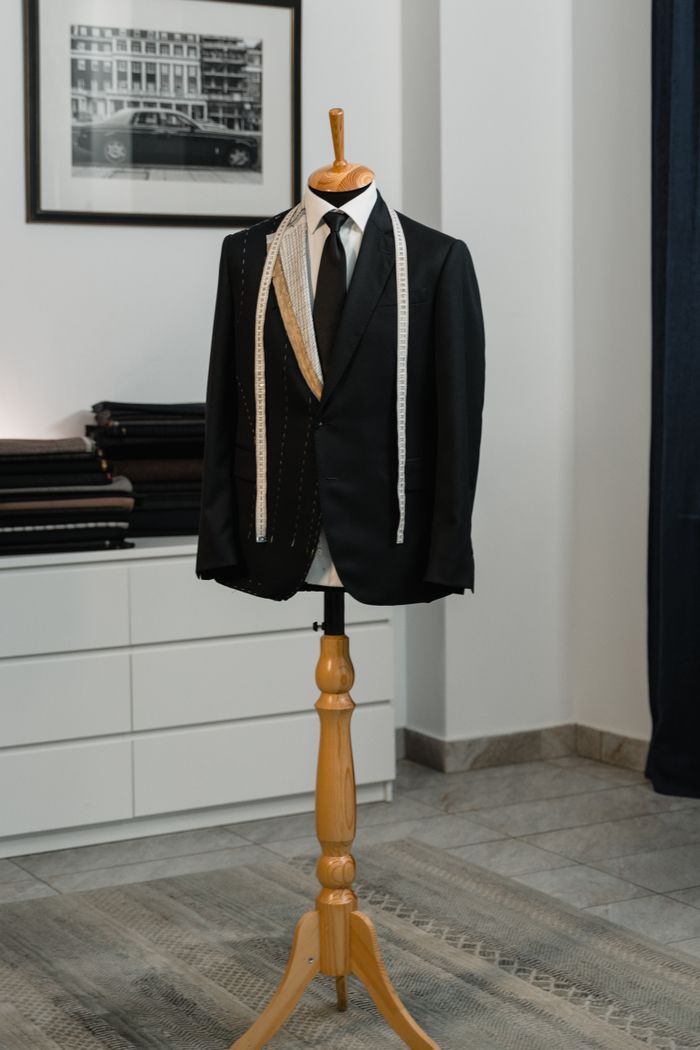 Mastering the First Impression: Your intriguing post title goes here A stylish black suit jacket displayed on a mannequin with a measuring tape, showcasing bespoke tailoring in an elegant studio setting.