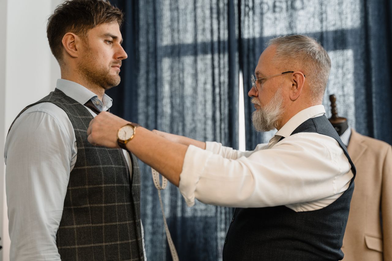 creative-01 Professional tailor measuring a client for a custom suit in a workshop setting.